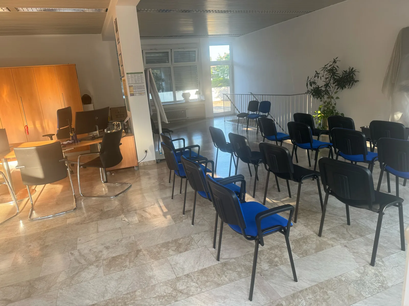 Büroplatz und Stuhlreihen im hellen Raum